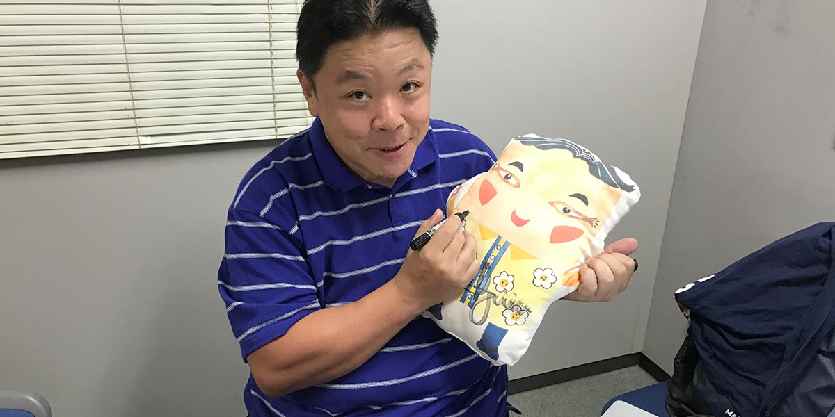 伊集院さんがクッションにサイン中